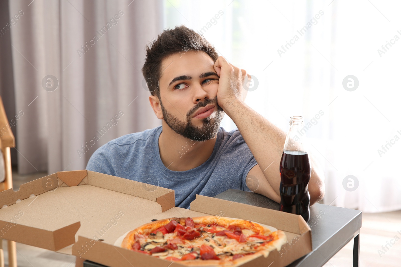 Photo of Lazy young man with pizza and drink at home