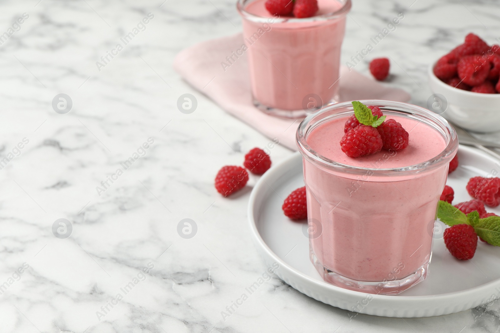 Photo of Delicious raspberry mousse with mint on white marble table, space for text