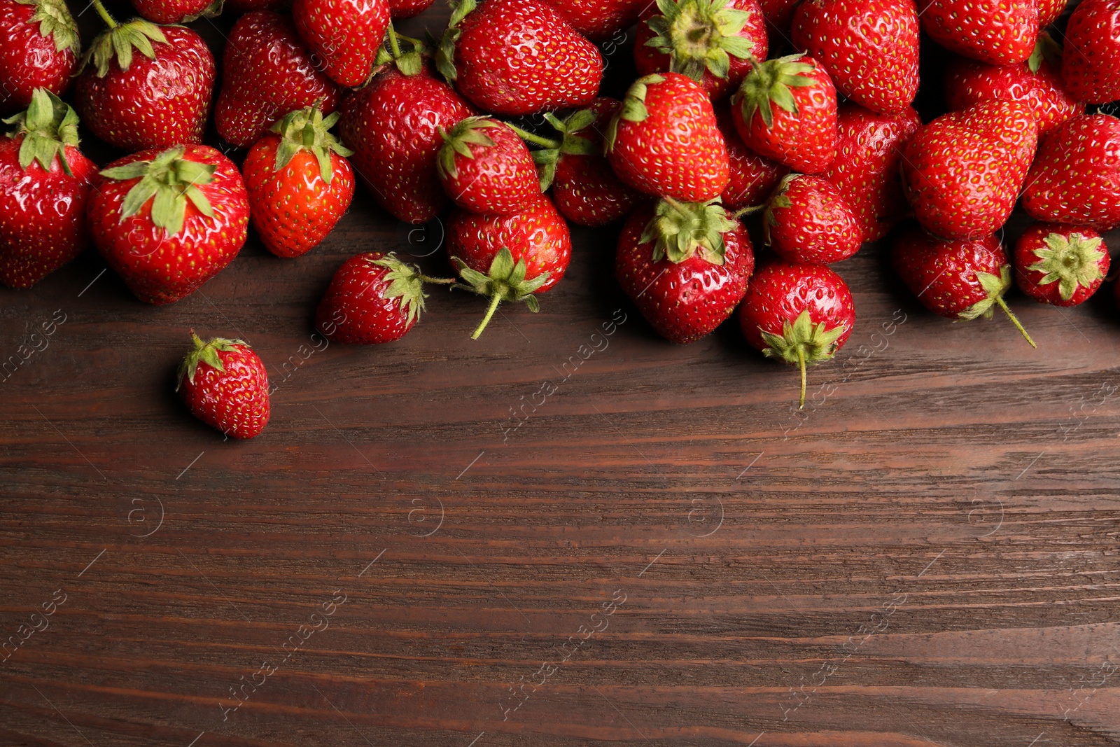 Photo of Delicious ripe strawberries on wooden table, flat lay. Space for text