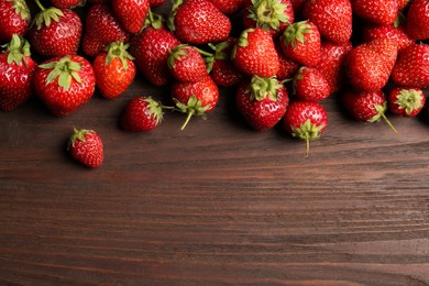 Delicious ripe strawberries on wooden table, flat lay. Space for text