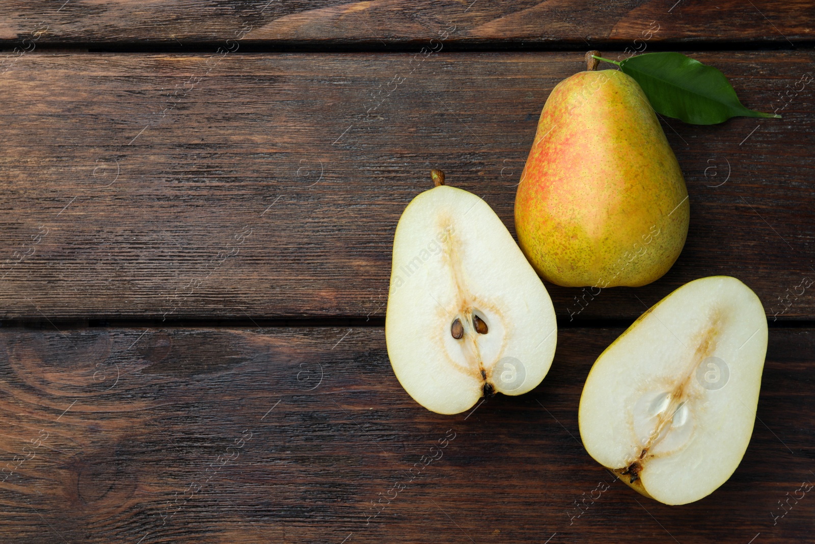 Photo of Whole and half of tasty fresh pears on wooden table, flat lay. Space for text