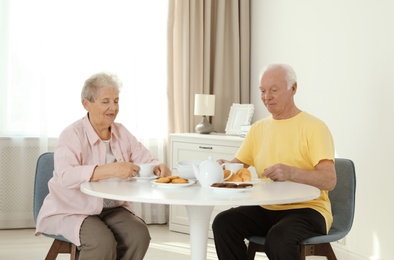 Elderly people having breakfast at nursing home. Assisting senior people