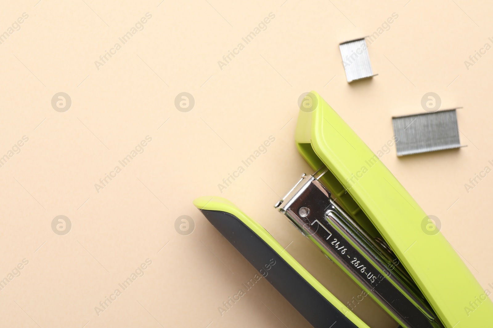 Photo of Bright stapler with staples on beige background, top view. Space for text