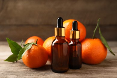 Bottles of tangerine essential oil and fresh fruits on wooden table