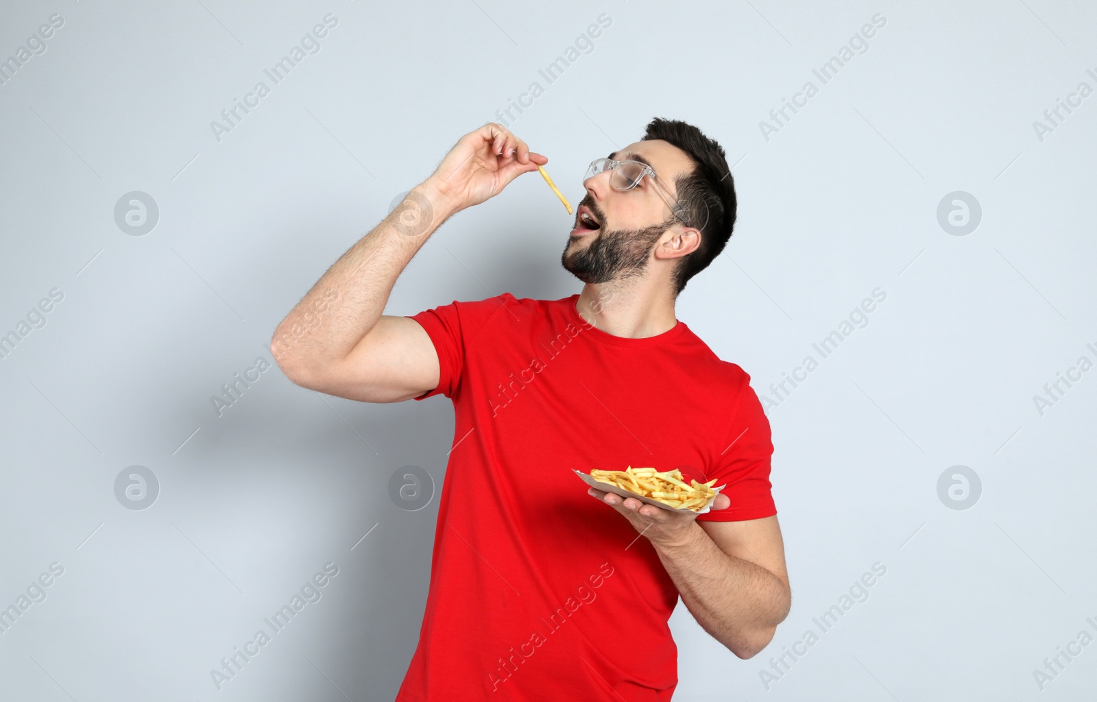 Photo of Man eating French fries on grey background