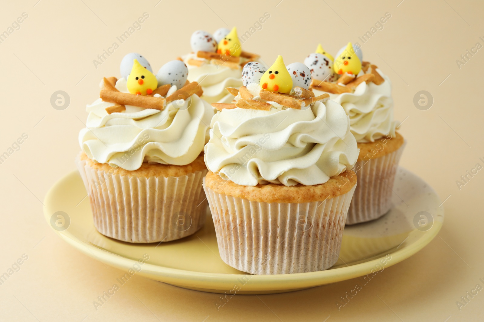 Photo of Tasty Easter cupcakes with vanilla cream on beige background