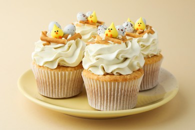 Tasty Easter cupcakes with vanilla cream on beige background