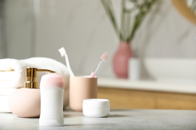 Photo of Stick deodorant and different toiletry on table in bathroom, space for text