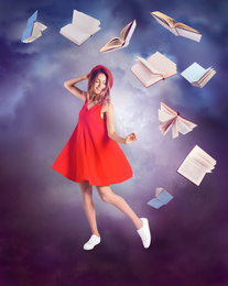 Beautiful young woman in red dress dancing and flying books on color background 