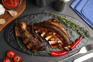 Delicious roasted ribs served on black table, flat lay