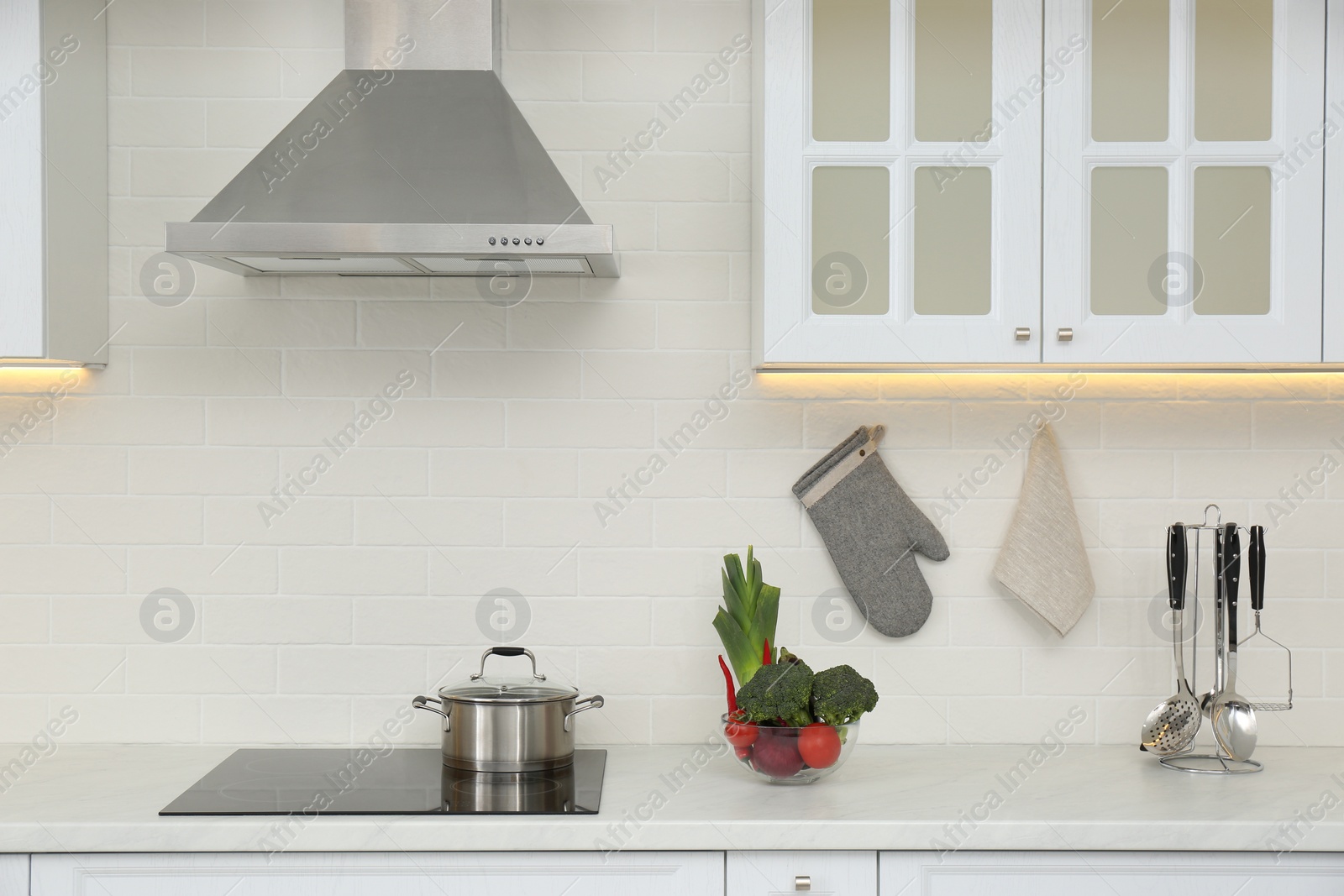 Photo of Pot on stove and fresh vegetables in modern kitchen