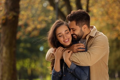 Photo of Beautiful couple hugging in autumn park, space for text