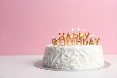 Photo of Birthday cake with candles on table against color background