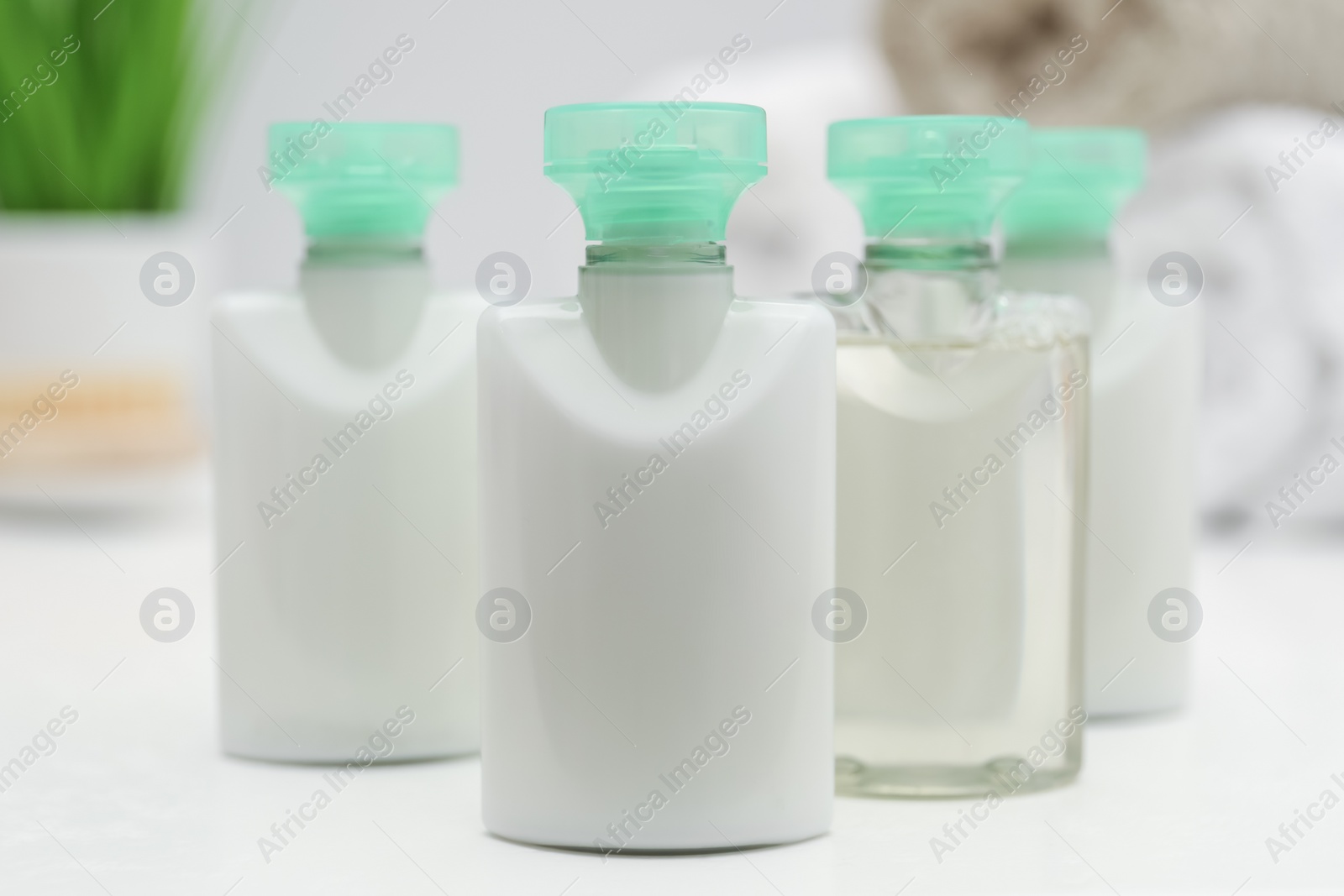 Photo of Mini bottles of cosmetic products on white table, closeup