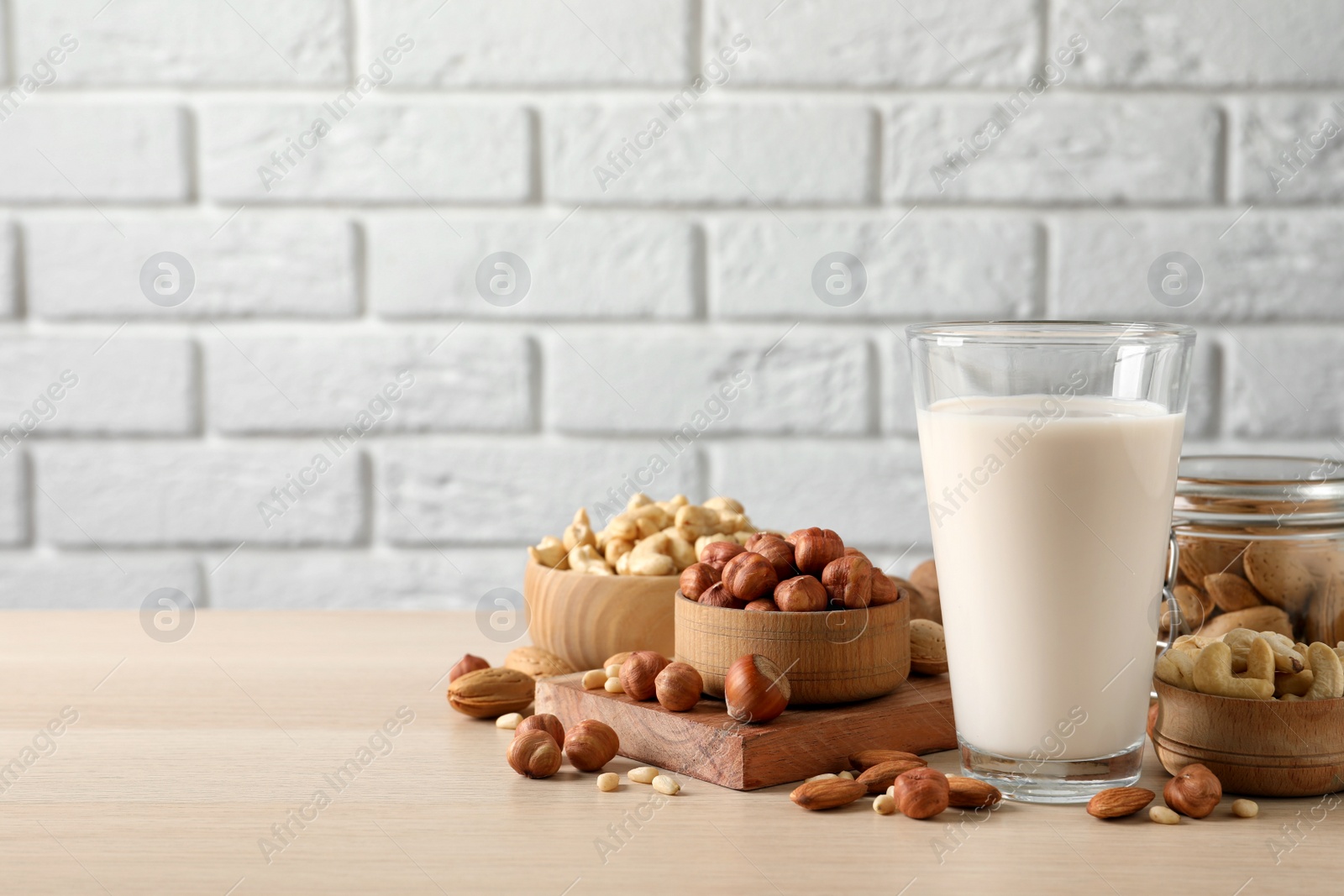 Photo of Vegan milk and different nuts on wooden table. Space for text