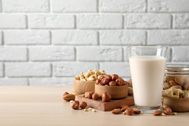 Photo of Vegan milk and different nuts on wooden table. Space for text