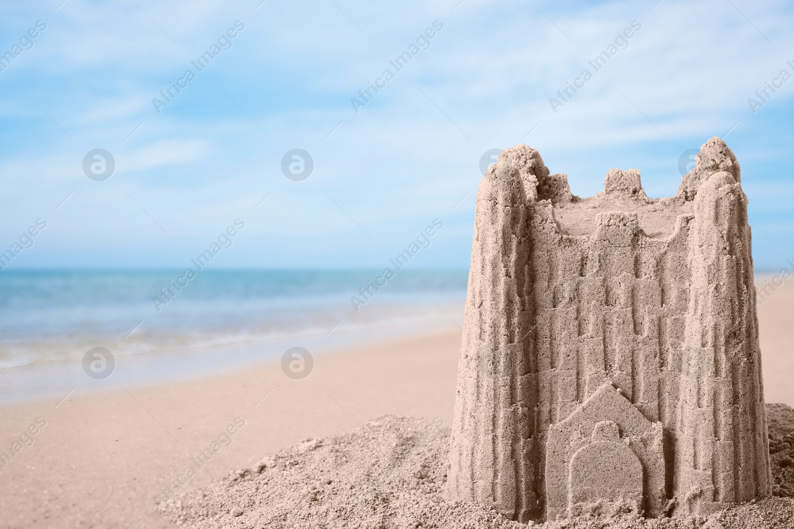 Image of Sand castle on ocean beach, space for text. Outdoor play