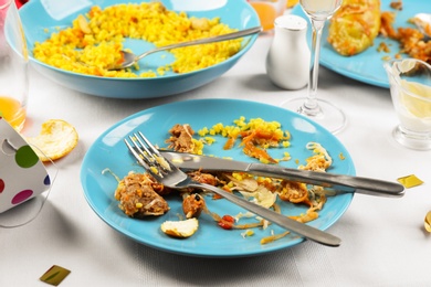 Photo of Dirty plate with leftovers on white tablecloth after party