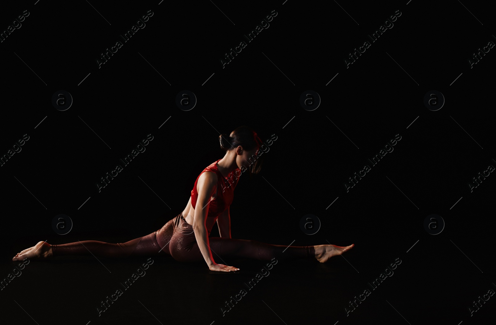 Photo of Young woman performing acrobatic element on stage indoors