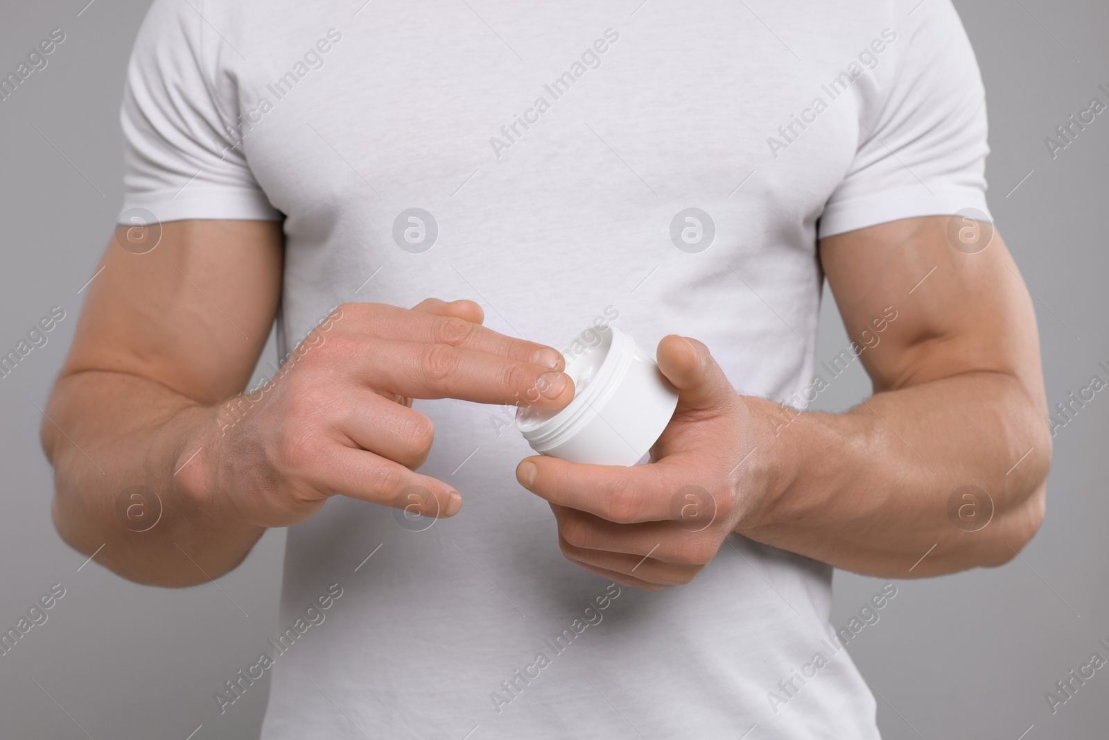 Photo of Man applying body cream on light grey background, closeup