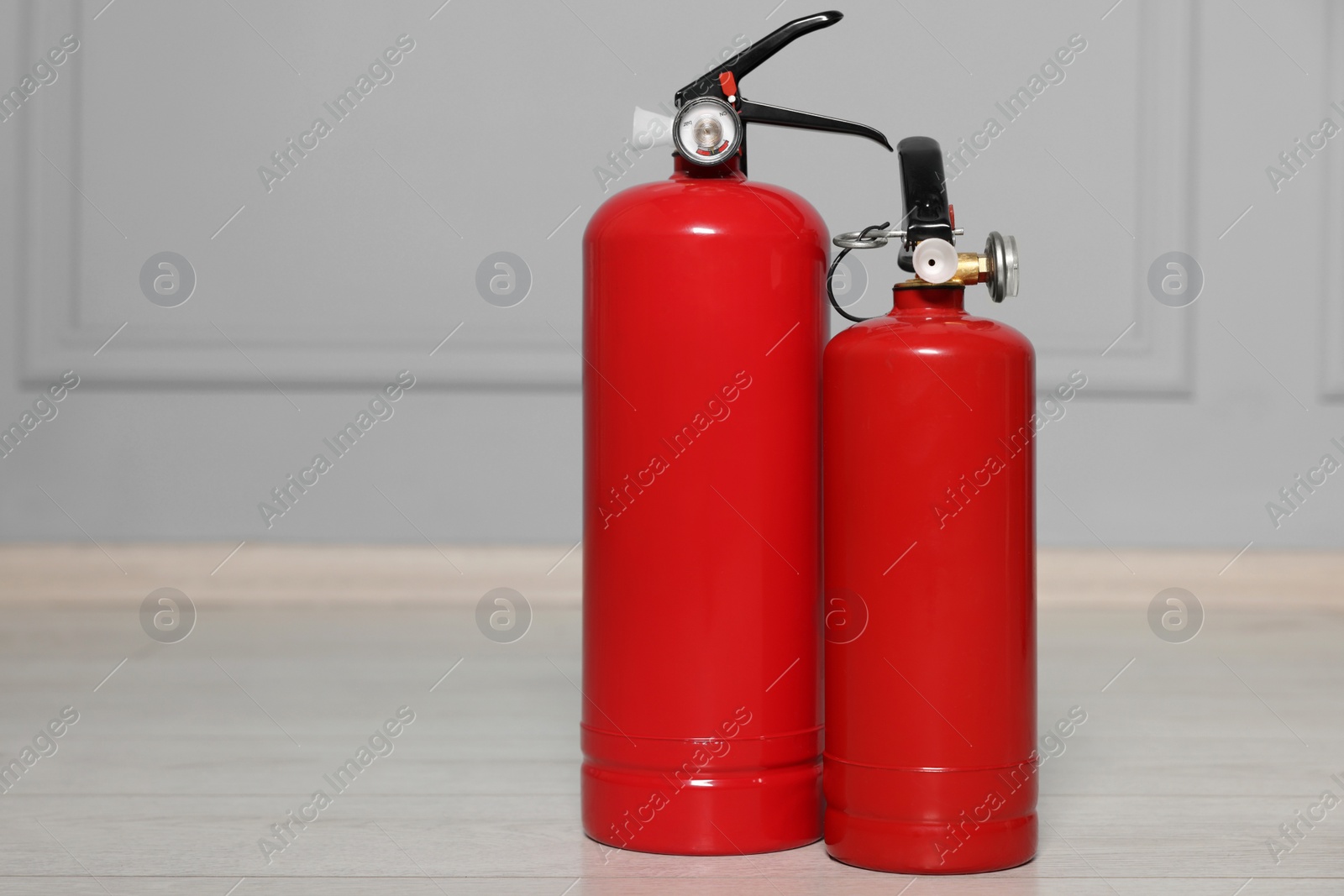 Photo of Red fire extinguishers near grey wall, space for text