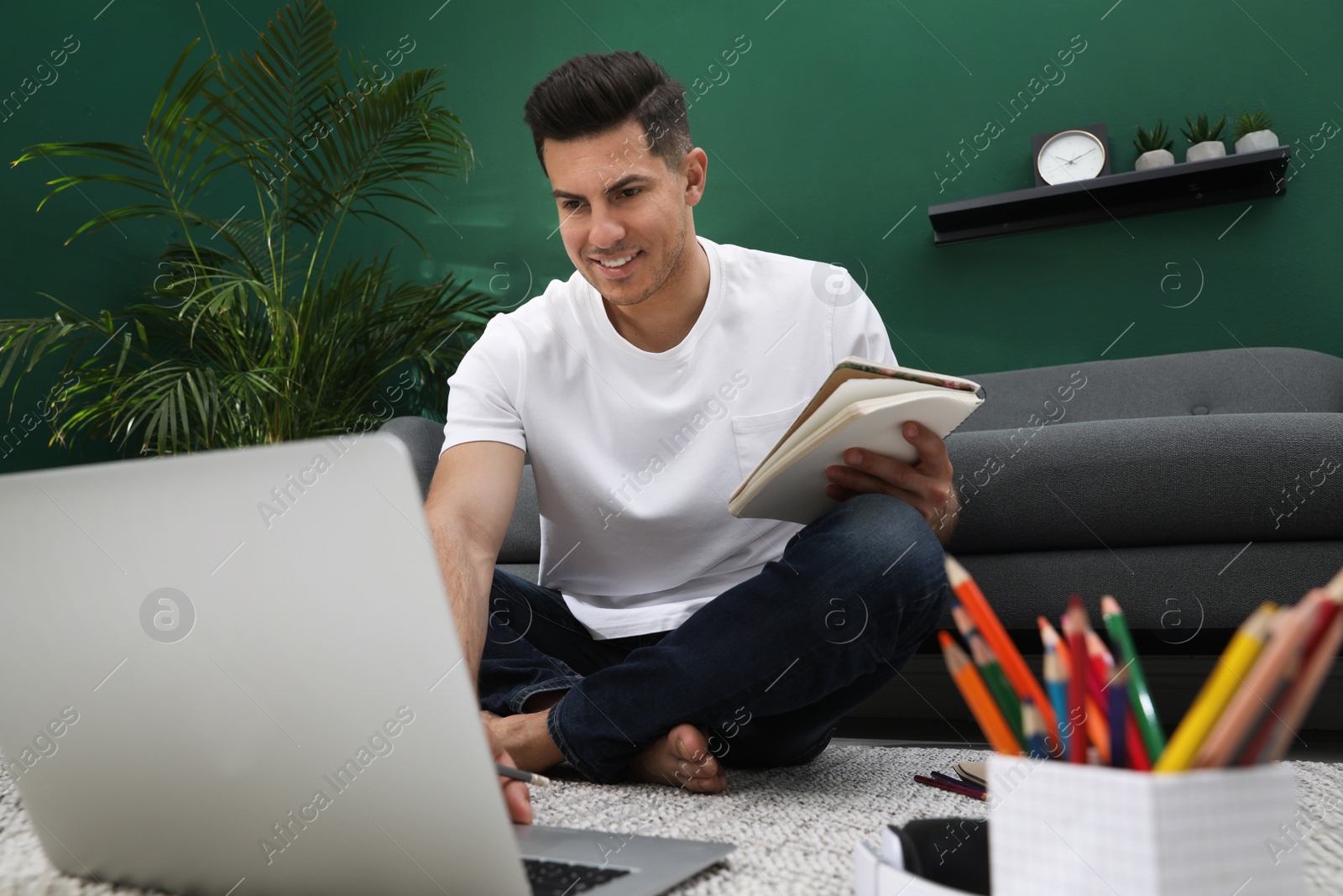 Photo of Man drawing in notebook at online lesson indoors. Distance learning