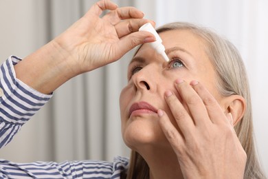 Photo of Woman applying medical eye drops at home