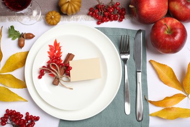 Beautiful autumn place setting with blank card and decor on table, flat lay