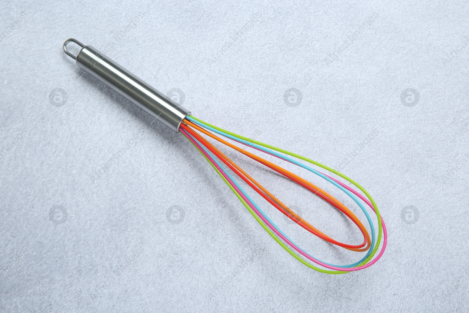 Photo of Bright whisk on gray table, top view. Kitchen tool