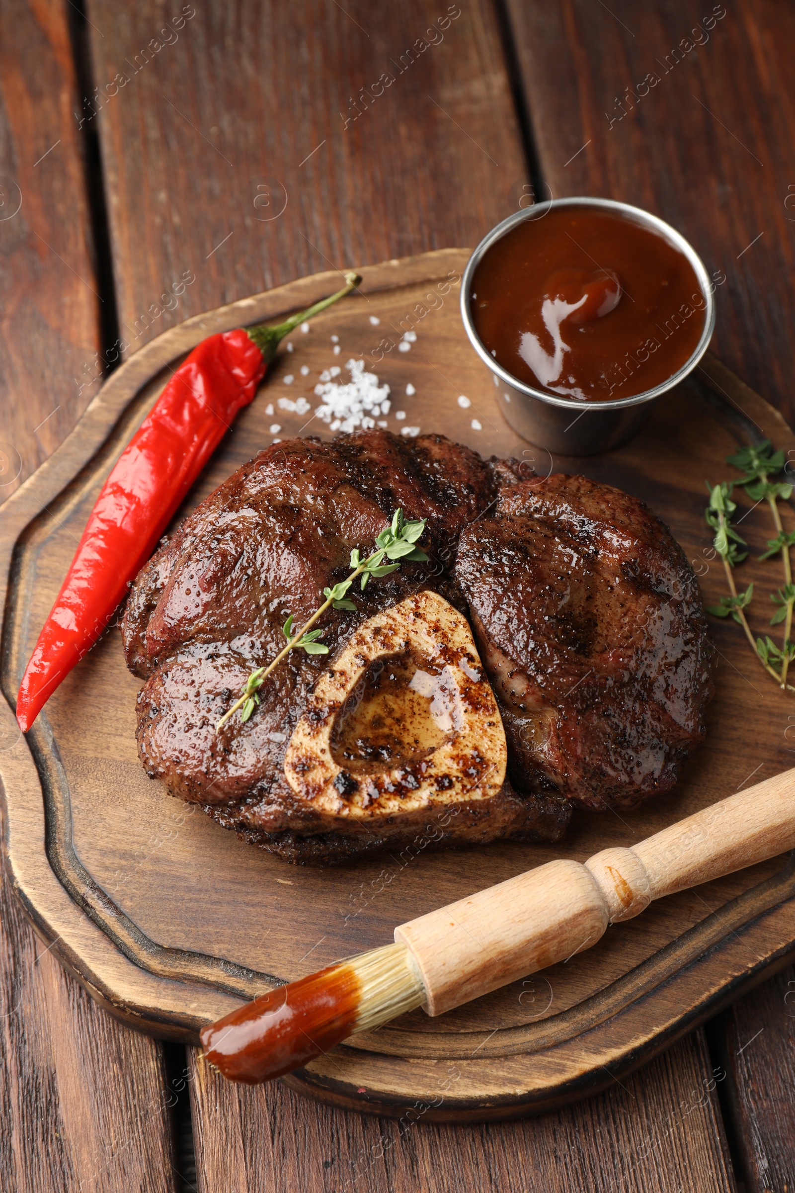 Photo of Delicious roasted beef meat served with sauce and spices on wooden table