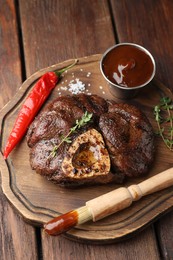 Delicious roasted beef meat served with sauce and spices on wooden table