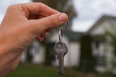 Real estate agent holding keys to new house outdoors, closeup