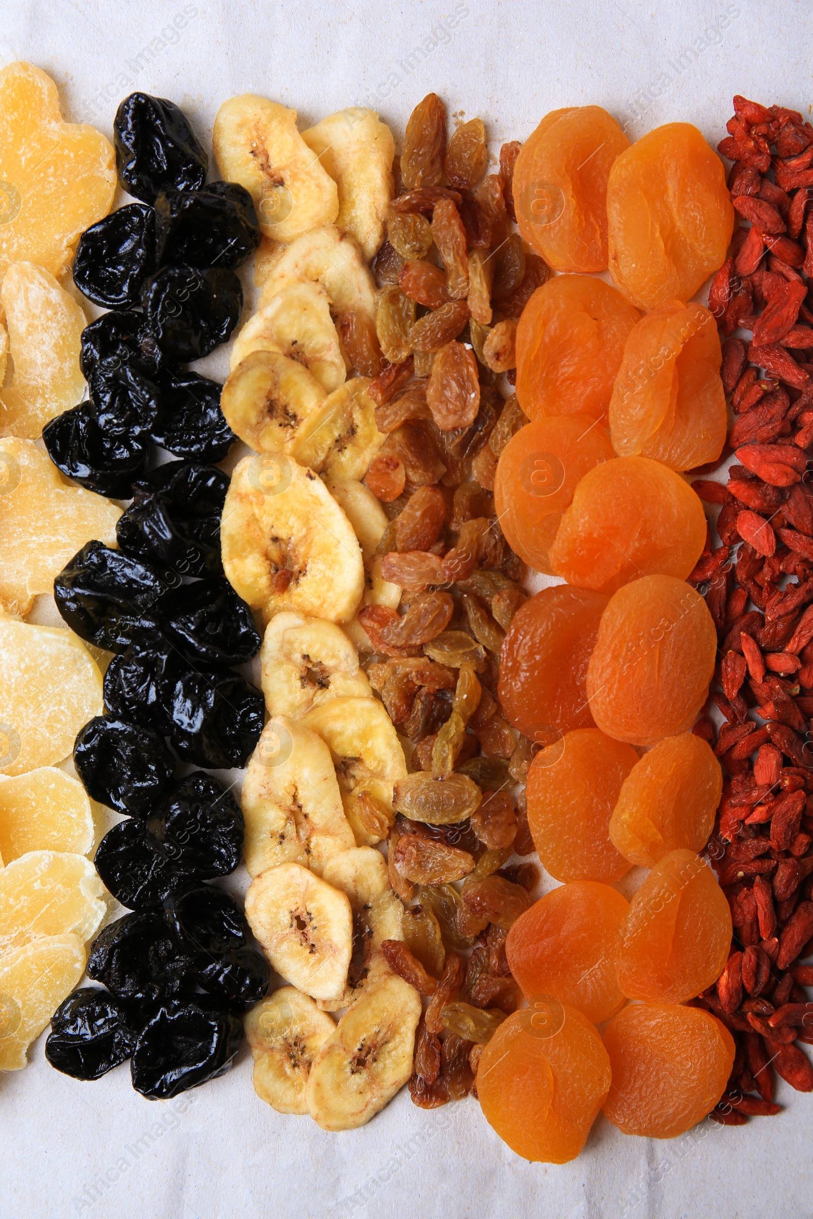 Photo of Different tasty dried fruits on paper, flat lay