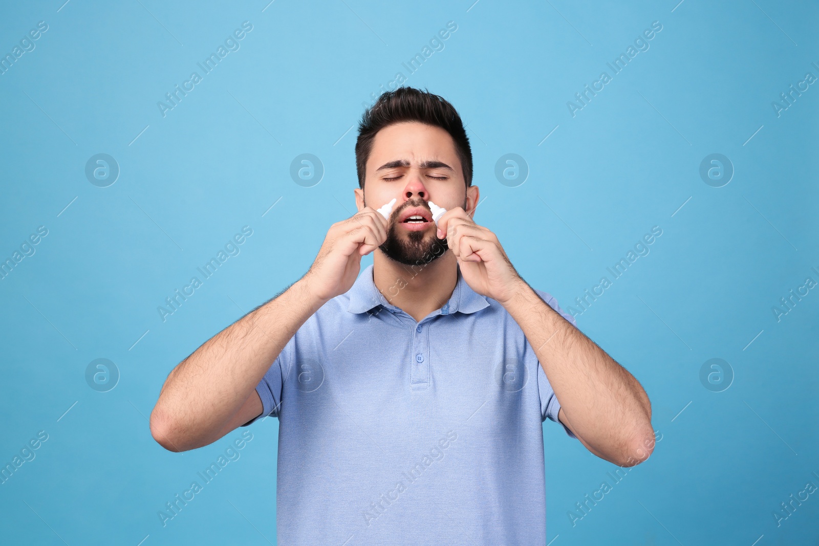 Photo of Man using nasal sprays on light blue background