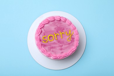 Image of Apology. Cake with word Sorry of cream on light blue background, top view