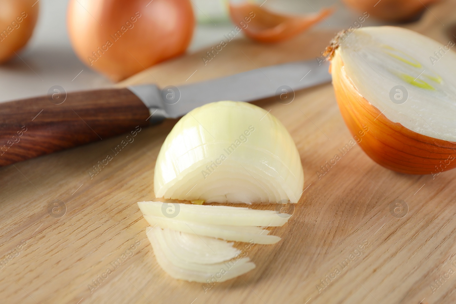 Photo of Whole and partially sliced onion on wooden table, closeup