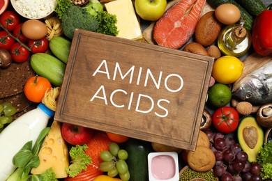 Image of Wooden board with text AMINO ACIDS among different products, top view 