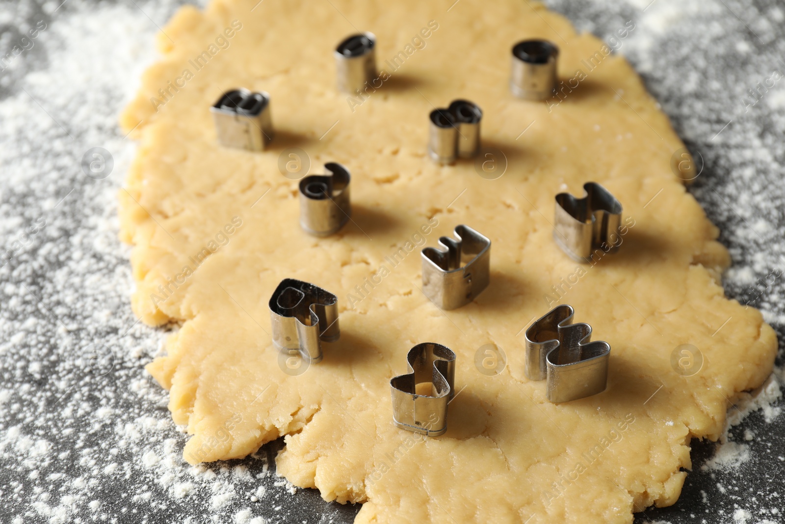 Photo of Making shortcrust pastry. Raw dough and cookie cutters on grey table