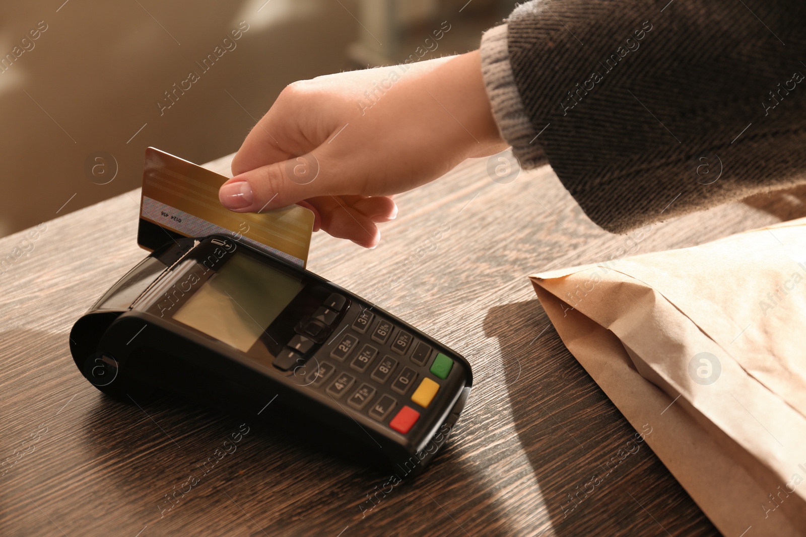 Photo of Woman with credit card using payment terminal at shop, closeup