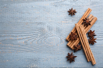 Aromatic cinnamon sticks and anise on grey wooden table, flat lay. Space for text