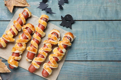 Cute sausage mummies served on blue wooden table, flat lay with space for text. Halloween party food