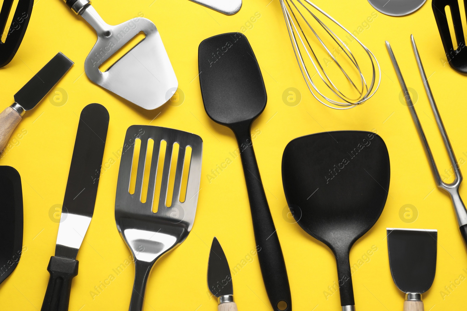 Photo of Different spatulas and other kitchen utensils on yellow background, flat lay