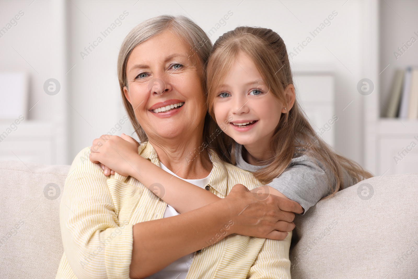 Photo of Happy grandmother hugging her granddaughter at home