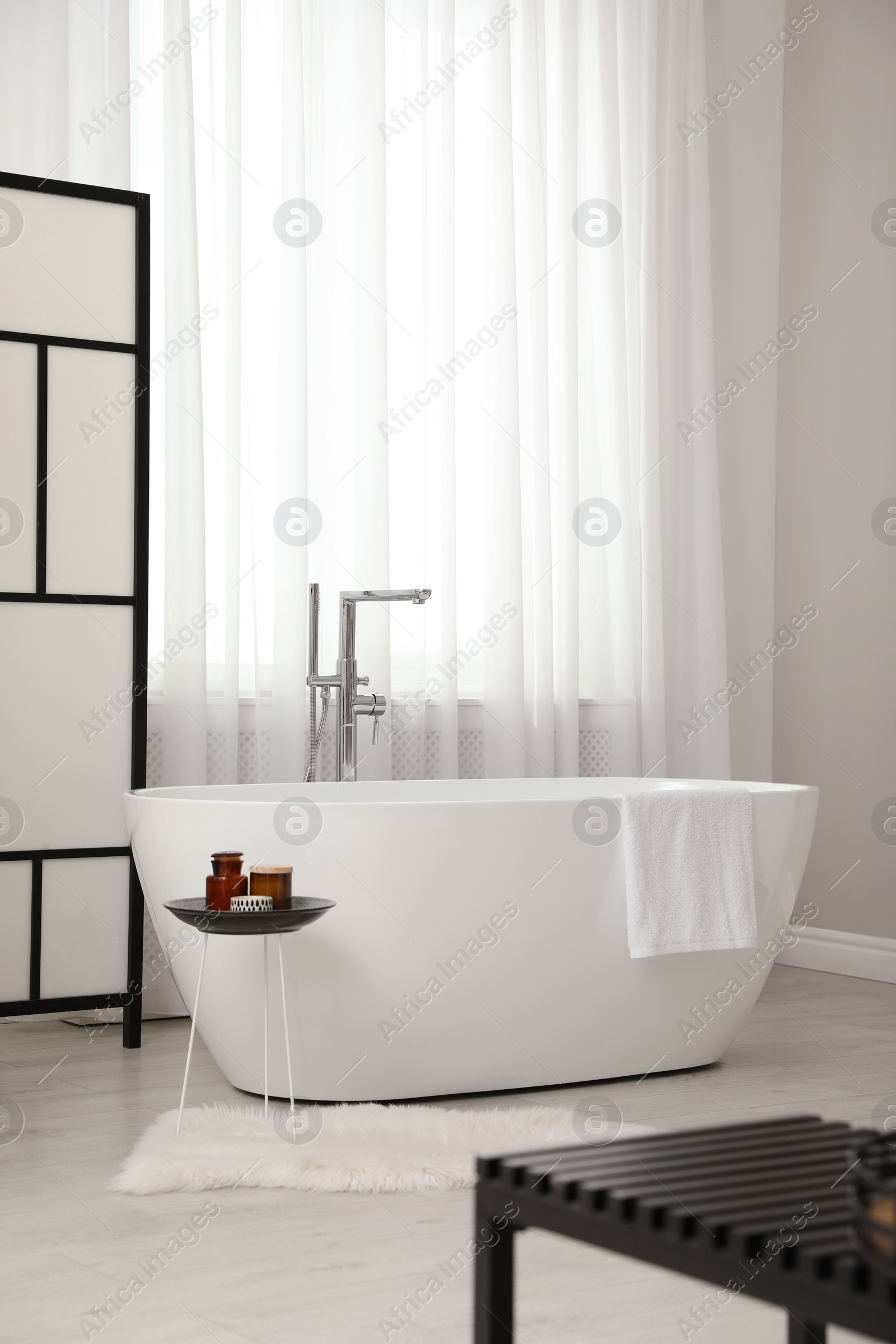 Photo of White tub near window in light room. Interior design