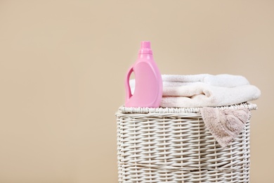 Photo of Wicker laundry basket with dirty clothes, clean towels and detergent on color background. Space for text