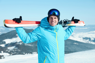 Photo of Happy man with ski equipment in mountains. Winter vacation