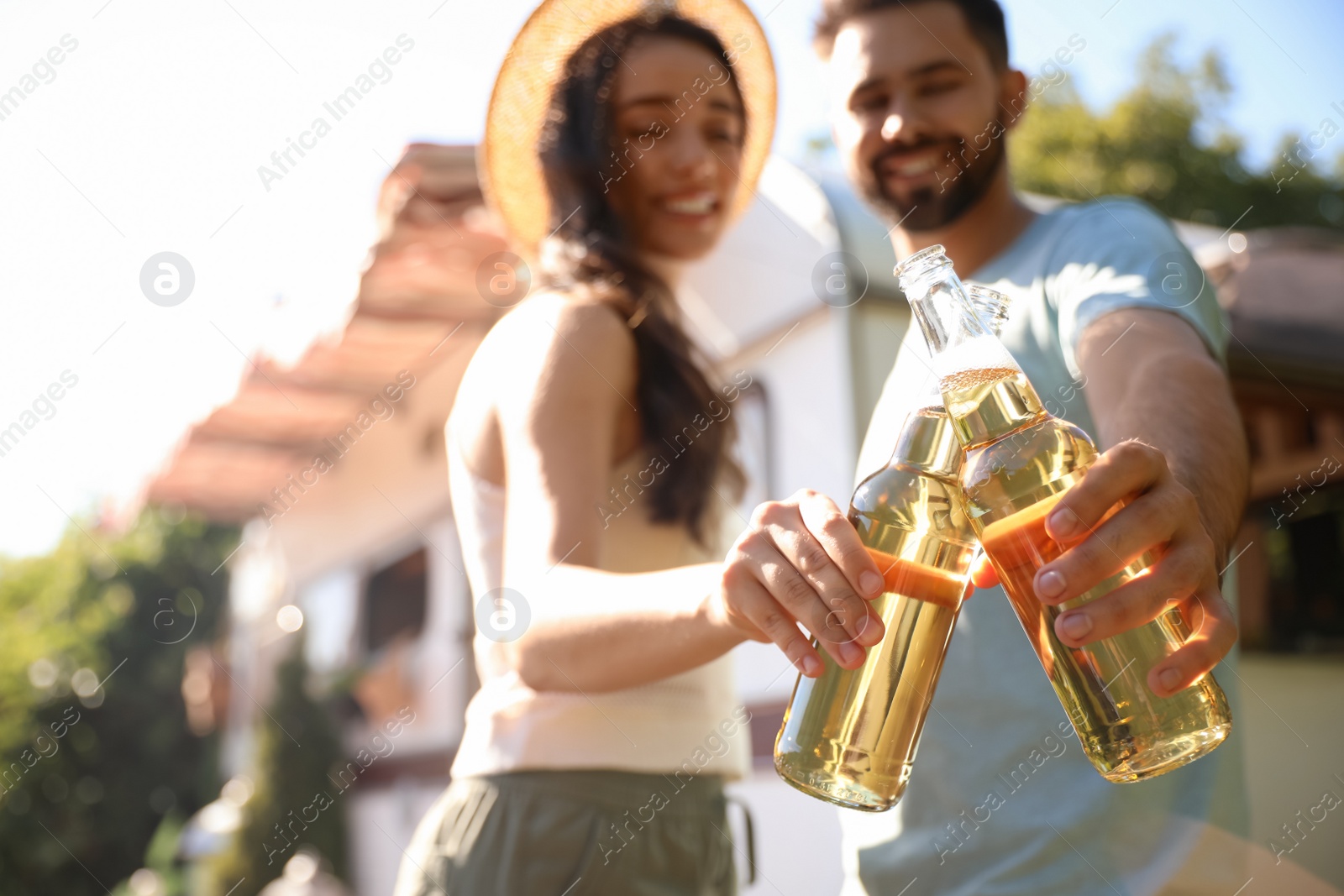 Photo of Young couple with bottles of beer outdoors, focus on hands. Camping season