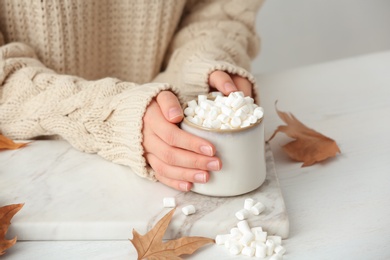 Photo of Woman in autumn sweater holding hot cozy drink at table