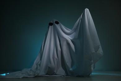 Creepy ghost. Woman covered with sheet on dark teal background