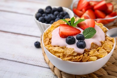 Photo of Delicious crispy cornflakes, yogurt and fresh berries in bowl on white wooden table, closeup with space for text. Healthy breakfast